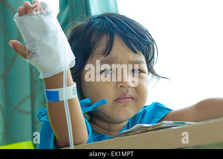 Malattia bambini asiatici gridare, seduto su una sedia in ospedale, soluzione salina per via intravenosa (IV) a portata di mano Foto Stock