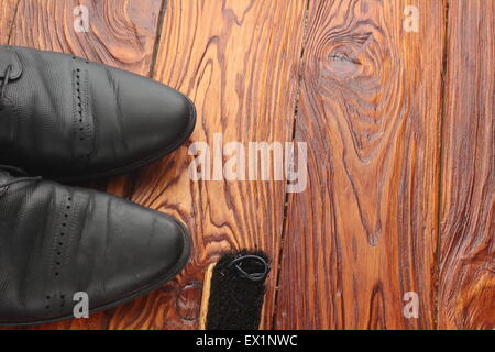 Su una tavola di legno che giace spazzola con lucidatura scarpe e calzature, uno su uno dei quali è usurata la crema Foto Stock