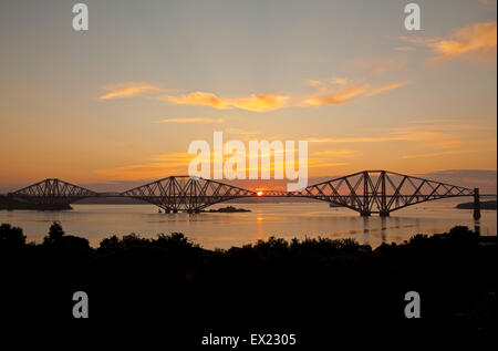 South Queensferry, Edimburgo, Scozia. 5 Luglio, 2015. Come il sole sorge dietro il Ponte di Forth Rail la riunione che era in corso a Bonn per decidere se il Ponte di Forth Rail dovrebbe diventare uno degli scozzesi i siti del Patrimonio Mondiale dell'Unesco, è stato annunciato che gli ispettori hanno deciso che la struttura dovrebbe essere raccomandato per l'approvazione, descrivendolo come "straordinario pietra miliare nella storia della costruzione di ponti". I membri dell'ONU il patrimonio comitato ha iniziato la loro tre giorni di riunione in Germania il 3 luglio. Foto Stock