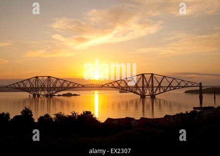 South Queensferry, Edimburgo, Scozia. 5 Luglio, 2015. Come il sole sorge dietro il Ponte di Forth Rail la riunione che era in corso a Bonn per decidere se il Ponte di Forth Rail dovrebbe diventare uno degli scozzesi i siti del Patrimonio Mondiale dell'Unesco, è stato annunciato che gli ispettori hanno deciso che la struttura dovrebbe essere raccomandato per l'approvazione, descrivendolo come "straordinario pietra miliare nella storia della costruzione di ponti". I membri dell'ONU il patrimonio comitato ha iniziato la loro tre giorni di riunione in Germania il 3 luglio. Foto Stock