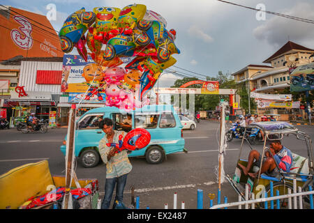 Un fornitore di palloncini mobili e un conducente di risciò in un contesto di traffico stradale su Penghibur Street a Makassar, Sulawesi meridionale, Indonesia. Foto Stock