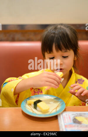 Bambina indossa uno yukata e mangiare sushi al ristorante. Foto Stock