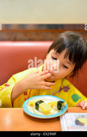 Bambina indossa uno yukata e mangiare sushi al ristorante. Foto Stock