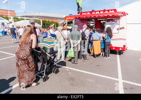 I clienti in coda fino a un gelato van in una giornata di sole Foto Stock