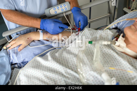 Muenster, Germania. 03 Luglio, 2015. Un infermiere aspira il sangue da un paziente in una convenzionale camera di unità di terapia intensiva presso l'ospedale universitario di Muenster, Germania, 03 luglio 2015. L'ospedale universitario ha presentato il nuovo concetto di spazio per la cura di cura intensiva di pazienti. Rumori come segnali acustici continui e allarmi disturbare i pazienti e il personale. Foto: Bernd Thissen/dpa/Alamy Live News Foto Stock