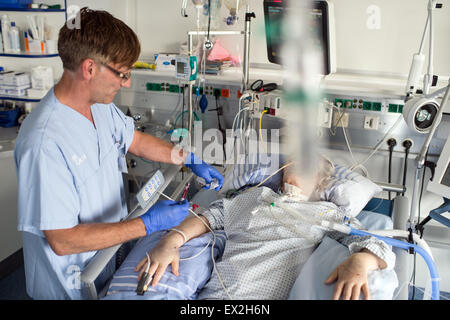 Muenster, Germania. 03 Luglio, 2015. L'infermiera Jan Terdenge aspira il sangue da un paziente in una convenzionale camera di unità di terapia intensiva presso l'ospedale universitario di Muenster, Germania, 03 luglio 2015. L'ospedale universitario ha presentato il nuovo concetto di spazio per la cura di cura intensiva di pazienti. Rumori come segnali acustici continui e allarmi disturbare i pazienti e il personale. Foto: Bernd Thissen/dpa/Alamy Live News Foto Stock