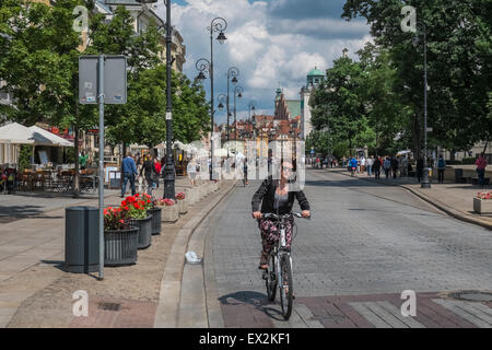 Giovane donna ciclismo su popolari Krakowskie Przedmieście Street, Città Vecchia, Varsavia, Polonia Foto Stock