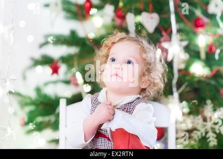 Bimbi felici ragazza con belle grandi occhi e capelli ricci controllando la sua calza di Natale Foto Stock