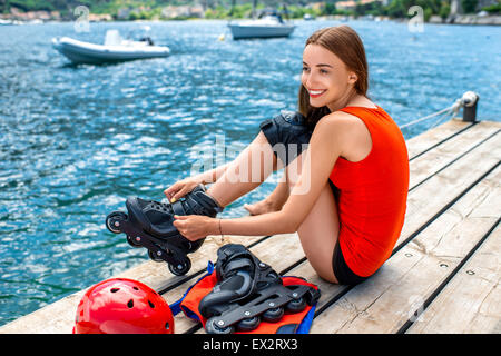 Donna in abbigliamento sportivo con rulli di pattinaggio sul molo Foto Stock