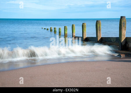 Le difese costiere e lavaggio onde sulla spiaggia a Teignmouth Beach, Devon, Inghilterra Foto Stock