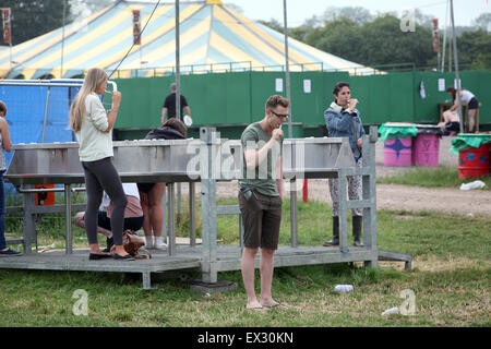 I frequentatori del festival, il lavaggio e la pulizia dei denti al mattino. Glastonbury 2015. Foto Stock