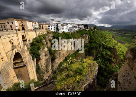 Nuvole scure e pezzata del sole sulla scogliera e nuovo ponte della città di montagna ronda spagna presso el tajo Gorge gola sul fiume Guadalevin Foto Stock