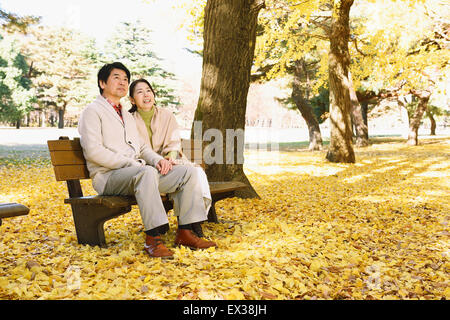 Senior coppia giapponese seduta su una panchina in un parco della città Foto Stock