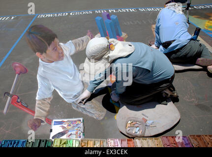 Una donna è la pittura con un gessetto il ritratto di un bambino che gioca al Imadonnari Street Painting Festival di Santa Barbara CA Foto Stock