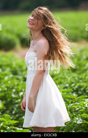 Una giovane donna in un campo verde e i capelli al vento. Kibbutz Ha'solelim, Israele Foto Stock