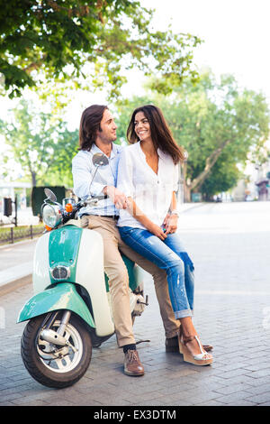 Felice coppia giovane su scooter guardando ogni altro all'aperto Foto Stock