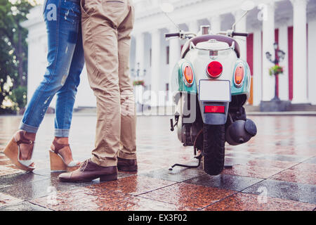 Immagine ritagliata di una coppia avente data in città. In piedi accanto a scooter Foto Stock