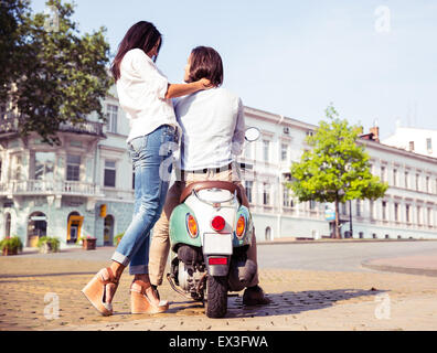 Ritratto di felice coppia giovane su scooter che si diverte in città europea Foto Stock