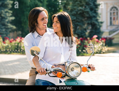 Coppia felice flirtare su scooter. Guardando a ciascun altro Foto Stock