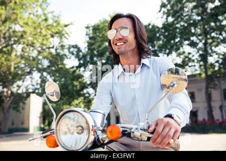 Ritratto di un felice elegante uomo su scooter Foto Stock