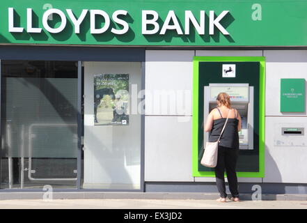 Una donna usa un bancomat macchina alla Banca di Lloyds succursale in Derbyshire England Regno Unito Foto Stock