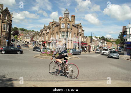 Un ciclista naviga fino alla rotatoria sulla piazza di corona in Matlock town center su una soleggiata giornata estiva, Derbyshire, Inghilterra Foto Stock