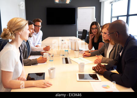 Un gruppo di giovani dirigenti tenendo una riunione di lavoro in una sala conferenze Foto Stock