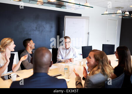 Gruppo di dirigenti applaudendo e sorridente al bianco collega di sesso maschile Foto Stock