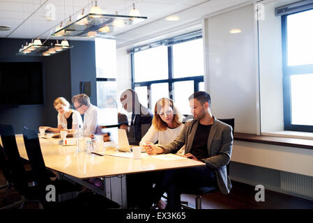 Un gruppo di giovani dirigenti di lavoro e di seduta al tavolo della sala conferenze Foto Stock