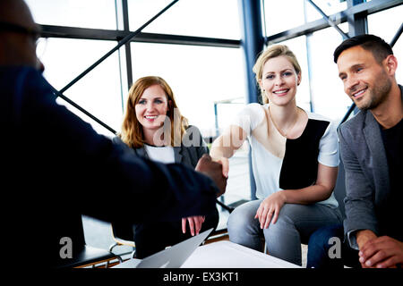 Femmina bianca di scuotimento executive collega la mano e sorridente in telecamera Foto Stock