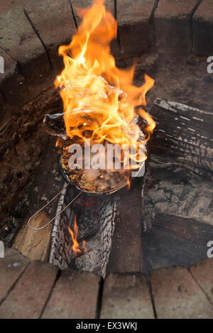 Il Popcorn in una lamina tegame coperto esplode e prende fuoco in un giardino una buca per il fuoco le fiamme con la masterizzazione ora popcorn immangiabile Foto Stock