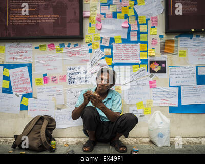 Bangkok, Bangkok, Thailandia. 6 Luglio, 2015. Un uomo scolpisce i giocattoli di legno sotto una parete ricoperta in ''Post It'' le note correlate all'arresto di 14 studenti per aver violato le prescrizioni correlate al gruppo politico. Più di un centinaio di persone si sono riuniti presso Università di Thammasat a Bangkok lunedì per mostrare il supporto per 14 studenti arrestati due settimane fa. Gli studenti sono stati arrestati per aver violato gli ordini contro il gruppo politico. Credito: ZUMA Press, Inc./Alamy Live News Foto Stock