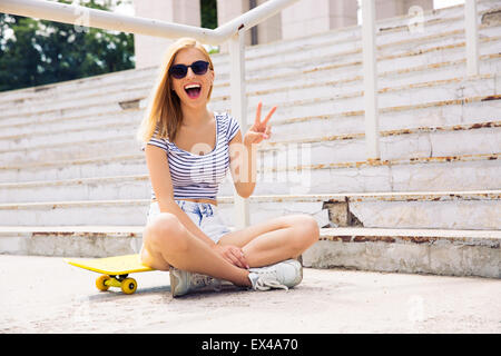 Allegro skater femmina che mostra due dita firmare all'aperto Foto Stock