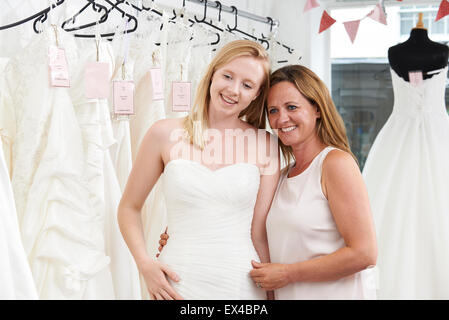 Madre aiutare mia figlia a scegliere abito nuziale In Store Foto Stock