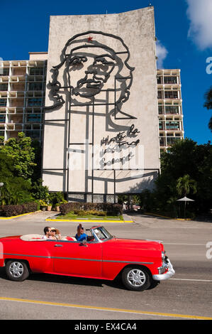 Vista verticale di turisti da parte di guida di Che Guevara murale in un vintage vecchia auto a l'Avana, Cuba. Foto Stock