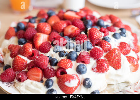 Pavlova cake con fragola, mirtillo, lampone e panna montata. Foto Stock