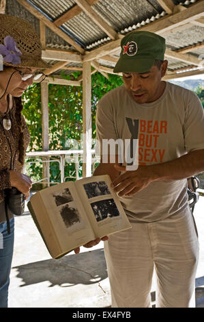 Ritratto verticale di un tour leader che mostra i turisti un libro su Fidel Castro Turquino nel Parco Nazionale di Cuba. Foto Stock