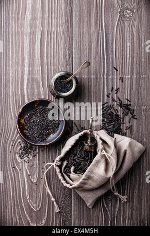 Nero cibo crudo ingredienti - riso selvatico, i semi di sesamo, sale nero su grigio Sfondo di legno Foto Stock