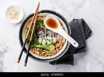 Miso Ramen Asian tagliatelle con i funghi shiitake, tofu e cavolo pak choi in ciotola su marmo bianco sullo sfondo Foto Stock
