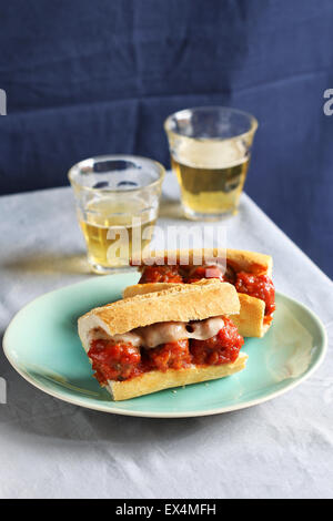 Due panini con le polpette su una piastra con due bicchieri di birra fresca Foto Stock