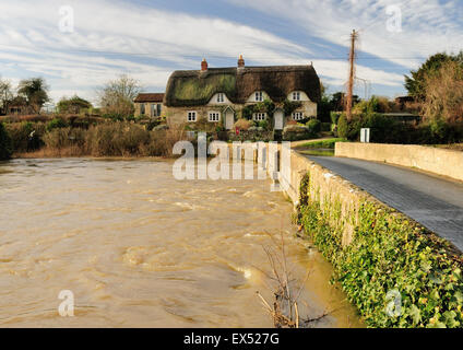 Cottage di paglia accanto al fiume gonfio Avon a Reybridge, vicino a Lacock, Wiltshire. Foto Stock