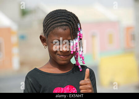 Il creolo ragazza con i capelli intrecciati decorate con perline colorate che mostra i pollici in su sull'isola di Boa Vista Capo Verde Foto Stock