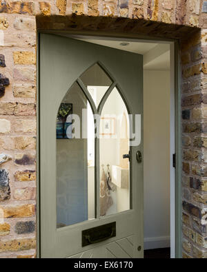 Porta anteriore con lo stile gotico della porta anteriore e del concio di mattoni e pietra focaia circondano Foto Stock