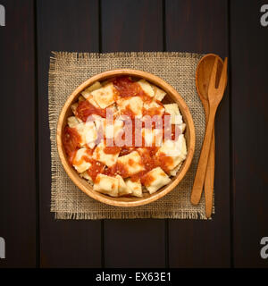 Cuocere i ravioli fatti in casa con salsa di pomodoro nel recipiente di legno con il cucchiaio di legno e la forcella sul lato, fotografato tettuccio Foto Stock