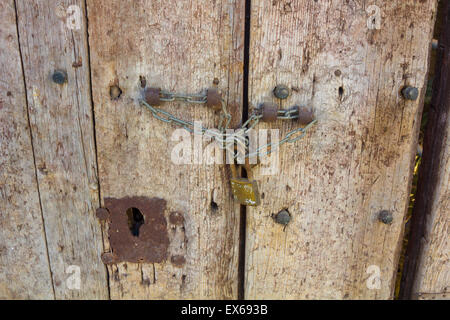 Vecchia porta di legno bloccato con una catena e un lucchetto Foto Stock