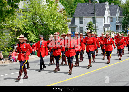 Un gruppo di Royal Canadian polizia montata RCMP ufficiali nel rosso uniforme cerimoniale marciando in un corteo guidato da un funzionario femmina Foto Stock