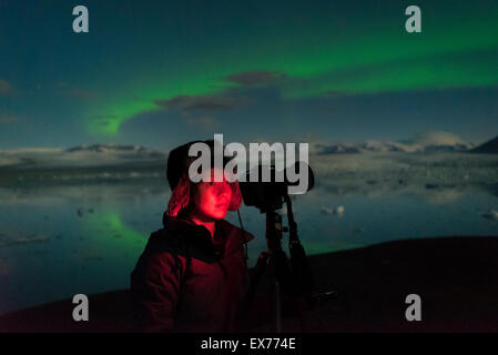 Donna di fotografare le aurore boreali a Jokulsarlon laguna glaciale, Islanda. Foto Stock