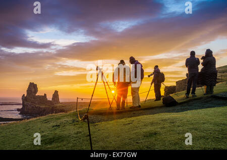 Il sole di mezzanotte e fotografi dal mare Londrangar pile e le scogliere Thufubjarg. Snaefellsnes Peninsula, Islanda Foto Stock