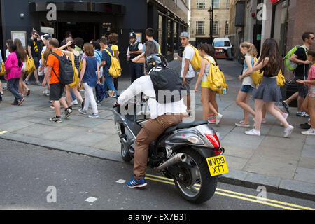 Estate a Londra, Inghilterra, Regno Unito. La folla di turisti e agli acquirenti di raccogliere in Leicester Square. Questo rimane uno di Londra turismo hot spot con animatori e shop e spazio per appendere fuori. Ci sono un gran numero di studenti che i gruppi turistici che si muovono intorno en masse. Foto Stock