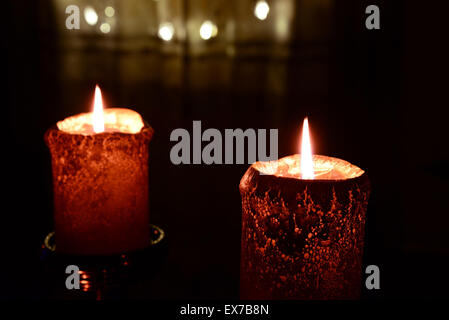 Due candele arancione sopra le luci di Natale Foto Stock